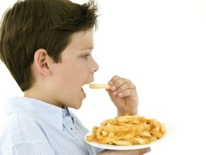Young boy eating French fries